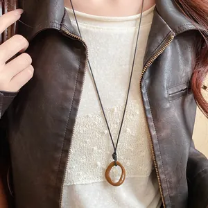 Detail view of a brown irregular geometric pendant on a minimalist black cord