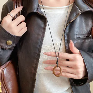 Close-up of neo-Chinese style brown irregular geometric ring necklace on model.