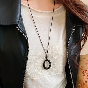 Close-up of black irregular geometric pendant necklace on a minimalist cord