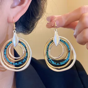 Detail shot of multilayered irregular gold and silver hoop earrings with blue accents