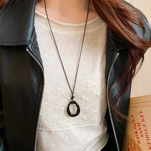 Close-up of black irregular geometric dripping oil necklace worn with leather jacket.