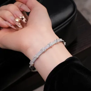Bracelet jonc argenté élégant avec zircons pavés et motif en croix au poignet du mannequin