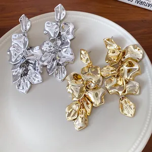 Primer plano de pendientes colgantes de pétalos de flores dorados y plateados