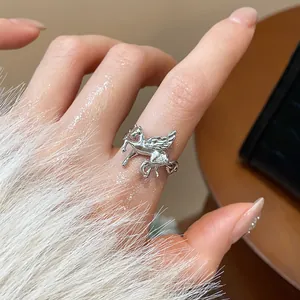 Detailed close-up view of an elegant silver Pegasus open ring worn on a hand with white fur