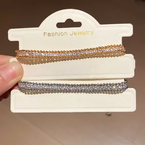 Close-up of elegant gold and silver rhinestone intertwined chain bracelets on card.