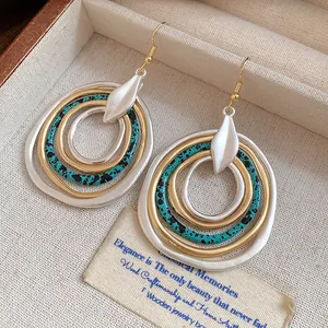 Macro view of vintage irregular multi-layer hoop earrings featuring gold, silver and teal finishes.
