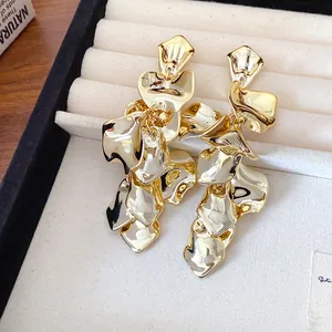 Primer plano de aretes florales de oro metálico vintage en una bandeja de joyas.