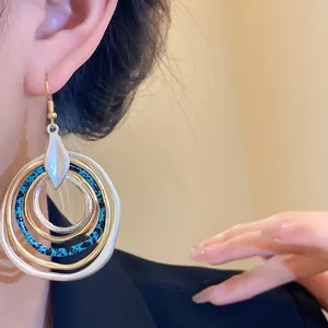 Close-up of irregular multi-layer circular dangle earrings with blue speckled pattern