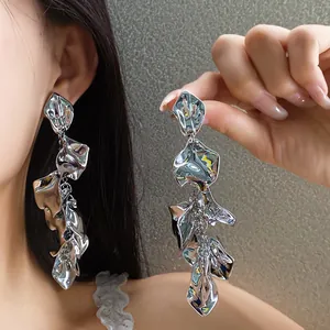 Vista detallada de pendientes largos de flores metálicas con acabado de espejo plateado
