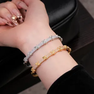 Détail de joncs élégants plaqués or et argent avec un motif en X croisé et des oxydes de zircon