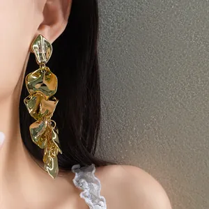 Primer plano detallado de pendientes largos de pétalos de flores de metal dorado en una modelo
