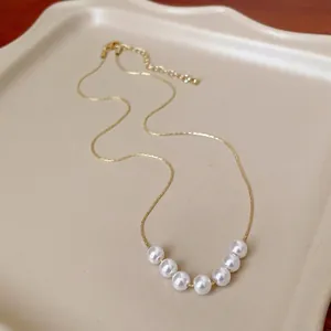 Collana girocollo con perle in stile francese e catena d'oro su vassoio beige
