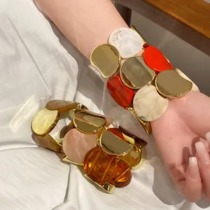 Primo piano di bracciali elastici in acrilico e metallo dorato sul polso