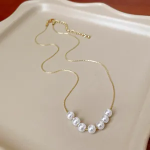 Dettaglio di una collana a catena dorata in stile francese con sette eleganti perle bianche
