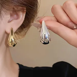 Detailed view of minimalist gold and silver teardrop earrings featuring a high-shine finish