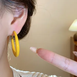 Detailed view of yellow enamel hoop earrings on ear, featuring a minimalist round design.