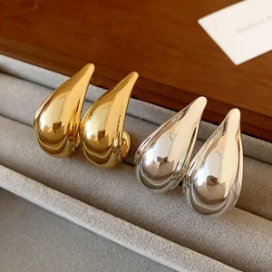 Close-up of minimalist gold and silver metallic water drop earrings on velvet tray