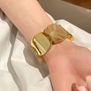 Primo piano di un bracciale elastico con maglie circolari in acrilico e finitura dorata