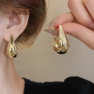 Close-up of minimalist gold metallic waterdrop stud earrings featuring elegant teardrop shape