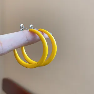 Close-up of vibrant yellow enamel hoop earrings with silver needles for daily wear