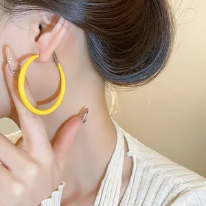 Detailed close-up view of bright yellow drip oil round hoop earring worn by a model
