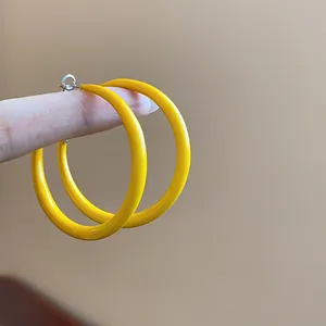 Close-up detail of vibrant yellow enamel hoop earrings featuring elegant silver needles