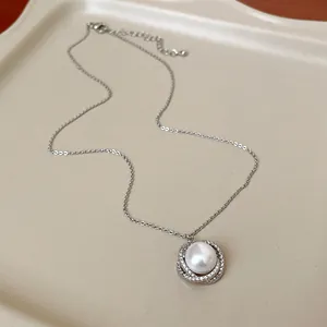 Dettaglio del ciondolo con perla bianca e cerchi in zirconi su catena d'argento elegante.
