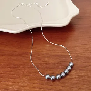 Dettaglio di una collana minimalista in stile francese con catena d'argento e perle grigie
