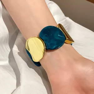 Vista ravvicinata di bracciale elastico con maglie circolari in acrilico e oro