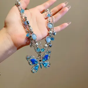 Dettaglio macro di una collana con farfalla a doppio strato e cristalli blu lucenti.