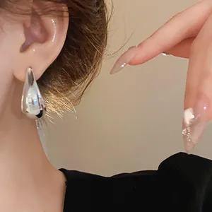 Detail shot of elegant silver-colored teardrop earrings worn on a female ear model