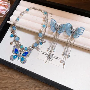 Dettaglio degli orecchini a farfalla in ricamo blu e collana di perline in set