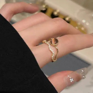 Dettaglio di un anello placcato oro con zirconi e una pietra occhio di gatto marrone.