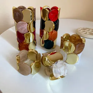 Vista dettagliata di bracciali elastici in acrilico con elementi placcati in oro