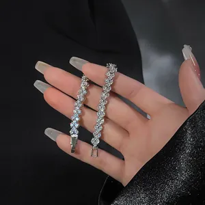 Detailed macro view of two shimmering silver-tone zircon tennis bracelets held on hand.