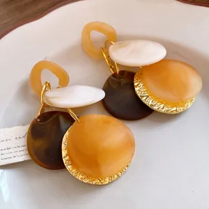 Dettaglio di orecchini vintage bohémien a dischi sovrapposti con trama ambra e marmo
