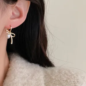 Close-up detail of Korean style bow-shaped earrings with a delicate pearl drop on model