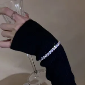 Detail shot of a sparkling zircon adjustable bracelet worn over a black knit sleeve