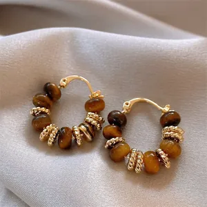 Detailed close-up of vintage golden hoop earrings with brown tiger eye stone beads