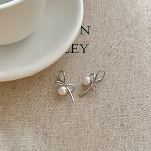 Detail view of Korean style silver ribbon bow earrings decorated with elegant white pearls