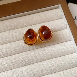 Dettaglio degli orecchini vintage a bottone color ambra in una scatola di lusso