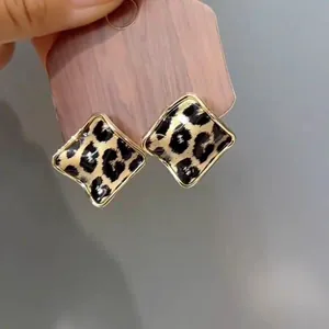 Dettaglio di orecchini a lobo vintage con stampa leopardata marrone e cornice dorata