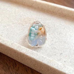 Detailed macro shot of a French retro ring featuring shells, beads and natural stones