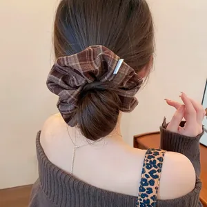 Close-up detail of a vintage brown plaid oversized scrunchie used in a low bun hairstyle