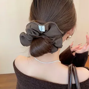 Detailed view of a brown pleated scrunchie styled on a low bun hair arrangement