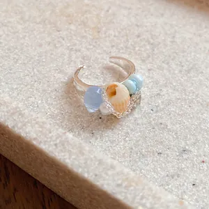 Close-up detail of French vintage silver ring with conch shell and light blue beads.