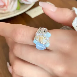Detailed macro view of a vintage French shell and blue stone beaded ring on finger