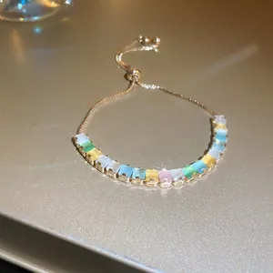 Elegante pulsera ajustable dorada con piedras preciosas rectangulares pastel.