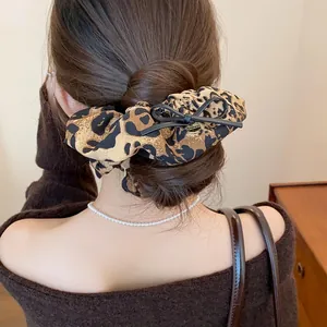Detailed view of a leopard print scrunchie with a bow on a low bun hairstyle.