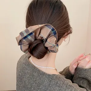 Detail shot of a vintage brown plaid scrunchie styled on a classic low hair bun.